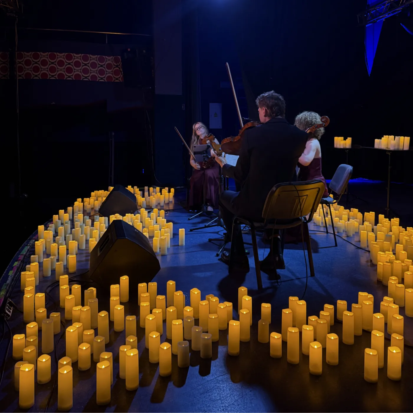 Muzycy w niebieskim świetle sceny, wokół świece
